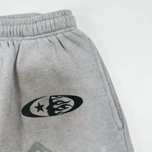 No brand or model info visible on close-up of grey sweatpants with black logo and pocket detail in cotton material