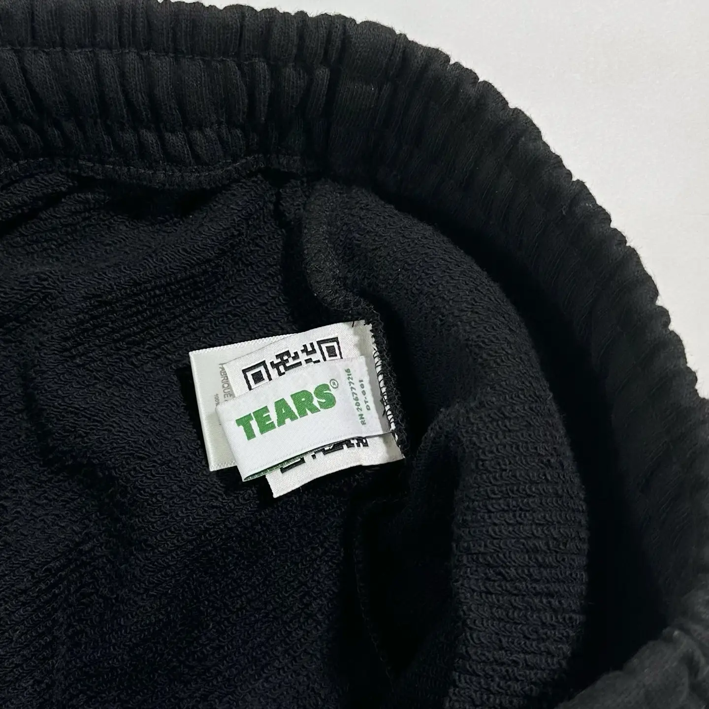 TEARS brand black cotton fabric with logo label and QR code tag close-up