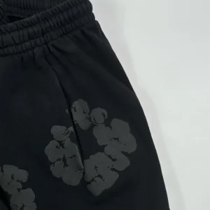 No brand or product type visible; image shows black fabric with subtle dark floral print and elastic waistband.