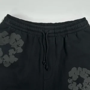Represent black sweatpants with elastic waistband and drawstring closure made of cotton material with floral print detail