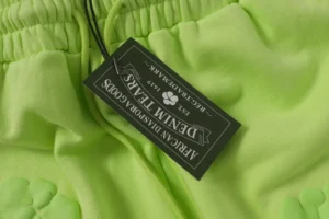 American Diaspora Goods denim tears lime green sweatpants cotton material with brand tag close-up