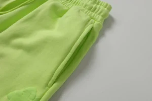 Denim Tears new cotton flower pants in fluorescent green, showcasing elastic waistband and side pockets, ideal for casual wear.
