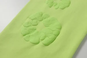 Close-up of textured green fabric featuring foam flower designs, related to Denim Tears new cotton flower pants available in various colors and sizes.