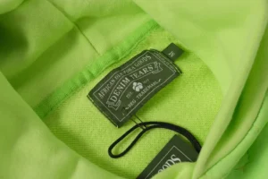 Denim Tears brand label on a vibrant green cotton hoodie from the Cotton Flower Collection.