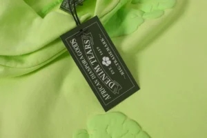 Casual looped hoodie from Denim Tears' Cotton Flower Collection, featuring a bright green fabric with foam flower details and a brand tag.