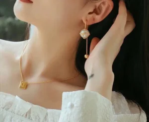 Dior Letter Pearl Earrings worn by a model, featuring a gold chain and pearl design, complementing a stylish outfit.