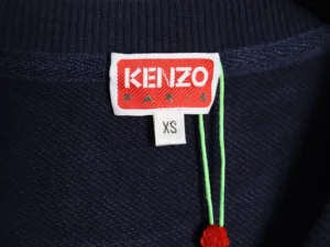 Kenzo clothing tag red white fabric label with green string and red flower accessory on navy material