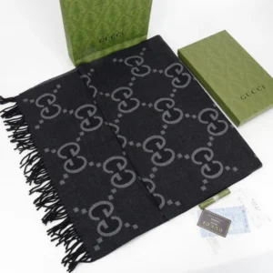 Gucci Big GG Double-Sided Jacquard Long Scarf displayed with luxury packaging, featuring a black design with gray GG logos and fringed edges, ideal for fashion enthusiasts.