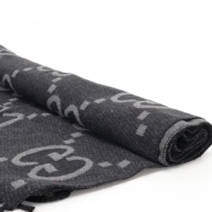 Gucci Big GG Double-Sided Jacquard Long Scarf showcasing rolled design with iconic GG logo pattern in dark tones, emphasizing luxury and style.