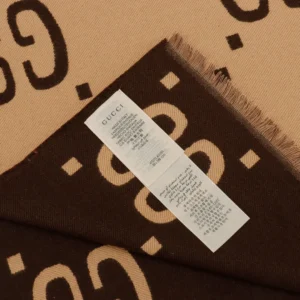 Gucci GG Large Logo Jacquard Wool Scarf showcasing the logo pattern and care label, emphasizing luxury and quality materials.