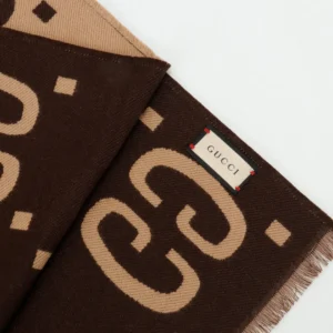 Gucci GG Large Logo Jacquard Wool Scarf featuring brown and beige colors, prominent GG logo pattern, and a Gucci label, showcasing luxury accessory design.