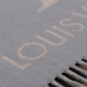 Close-up of Louis Vuitton gradient cashmere fringe scarf displaying logo and soft texture, emphasizing luxury fashion accessory.