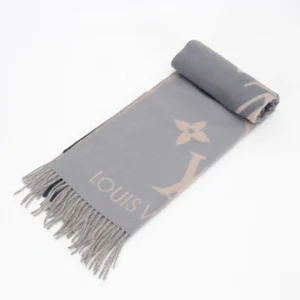 Louis Vuitton gradient cashmere fringe scarf displayed, featuring soft gray fabric with iconic logo design and fringed edges, emphasizing luxury accessory for purchase.