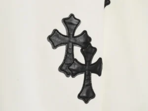 Leather cross pattern detail on Chrome Hearts hoodie, showcasing embroidered design on a white fabric background.