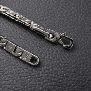 Louis Vuitton Monogram Tied bracelet featuring polished metal and intricately carved LV letters and Monogram flowers on a textured black background.