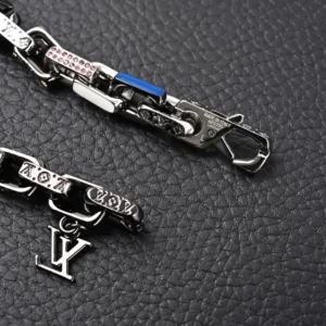 Louis Vuitton Chain Letter Embellished bracelet featuring large flat chain links, engraved LV logo, colorful enamel accents, and artificial crystals on a textured black background.