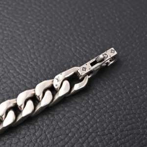 Louis Vuitton Monogram chain bracelet with engraved logo and clasp detail on textured background.
