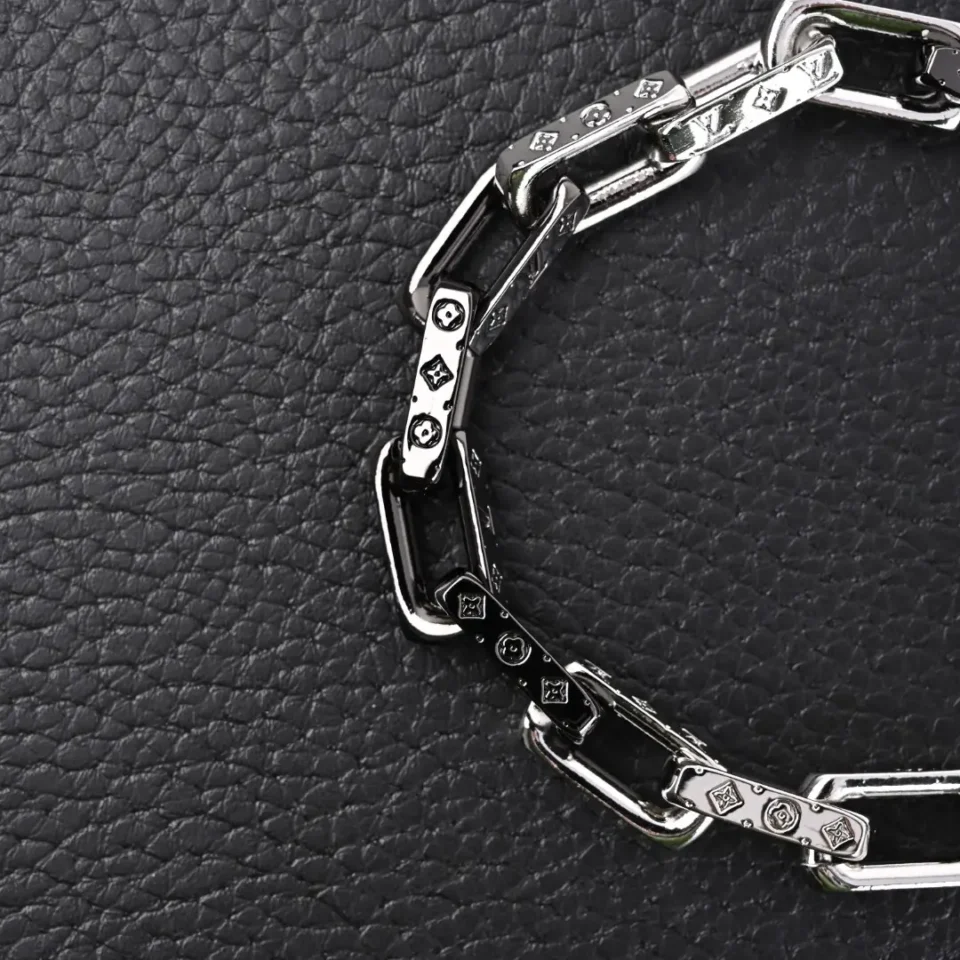 Louis Vuitton chain bracelet silver-tone metal with engraved monogram links on black textured background