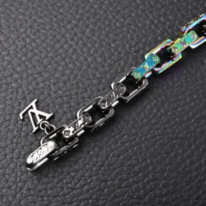 Multi-colored patchwork pendant bracelet by Louis Vuitton, featuring matte, polished, and glossy metal chain links with LV logo charm, displayed on textured black surface.