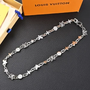 Louis Vuitton LV Monogram Craggy chrysanthemum necklace featuring glossy brass links with seasonal daisies, displayed on a black surface with an orange Louis Vuitton box in the background.