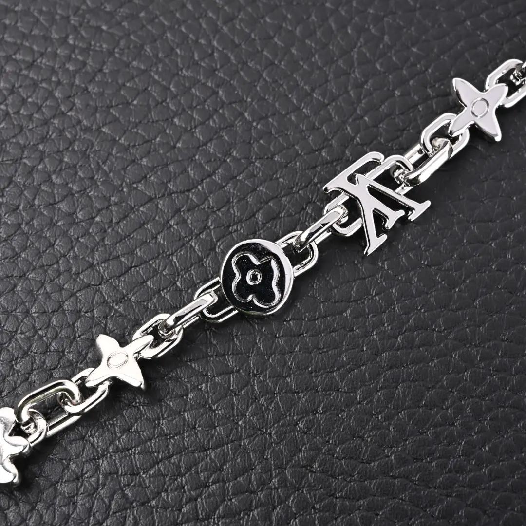 Louis Vuitton Monogram Craggy Chrysanthemum bracelet featuring glossy brass links and LV logo, set against a textured black background.