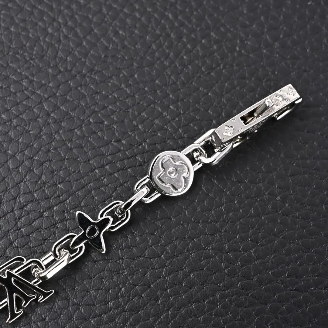 Louis Vuitton Monogram Craggy Chrysanthemum bracelet featuring glossy brass elements and LV logo, displayed on a textured black surface.