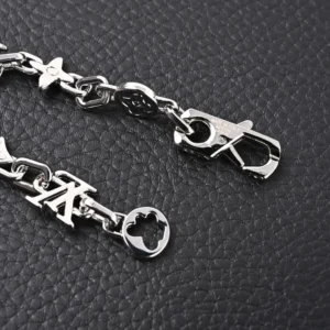 Louis Vuitton Monogram Craggy Chrysanthemum bracelet featuring glossy brass elements, LV logo, and clasp detail on textured black background.