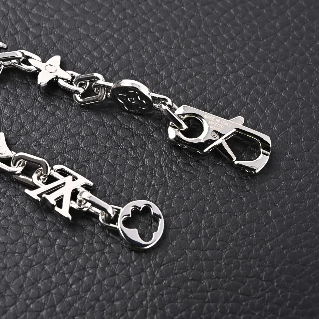 Louis Vuitton Monogram Craggy Chrysanthemum bracelet featuring glossy brass elements, LV logo, and floral motifs on a textured black background.