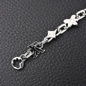 Louis Vuitton Monogram Craggy Chrysanthemum bracelet featuring LV logo and floral elements in glossy brass, set against a textured black background.