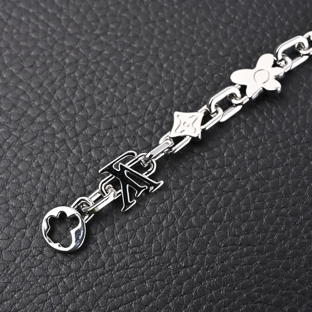 Louis Vuitton Monogram Craggy Chrysanthemum bracelet featuring glossy brass links, LV logo, and seasonal daisy elements on a textured black background.