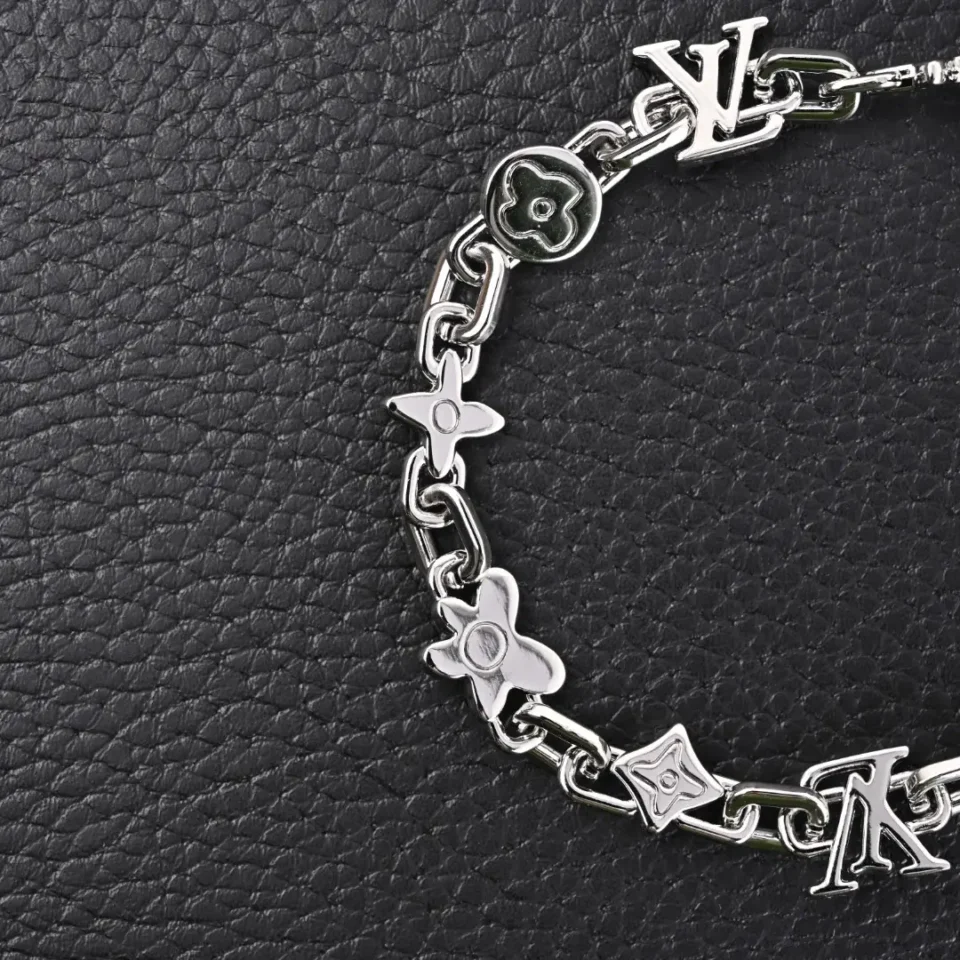 Louis Vuitton bracelet silver metal chain with iconic LV and floral motifs on black background