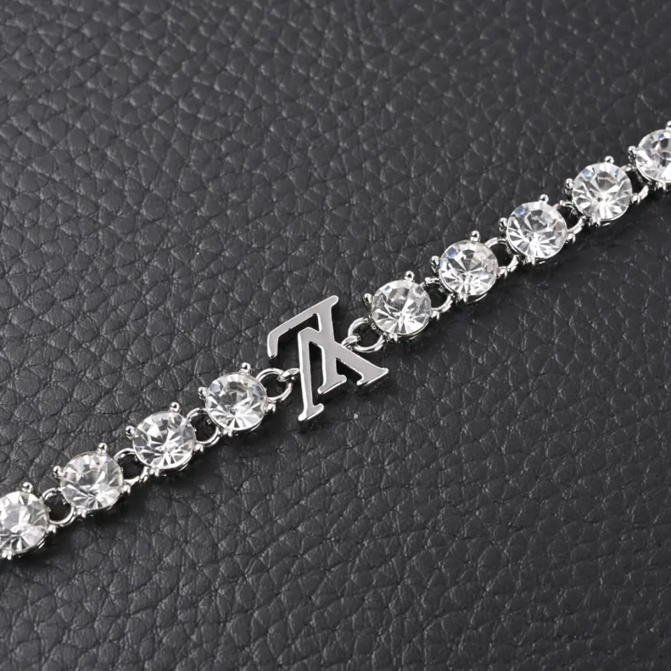 Tiffany & Co. tennis bracelet silver with round clear crystal stones and logo charm on black textured background