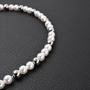 Louis Vuitton Monogram Pearls necklace featuring alternating pearl and polished metal beads on a dark leather background.