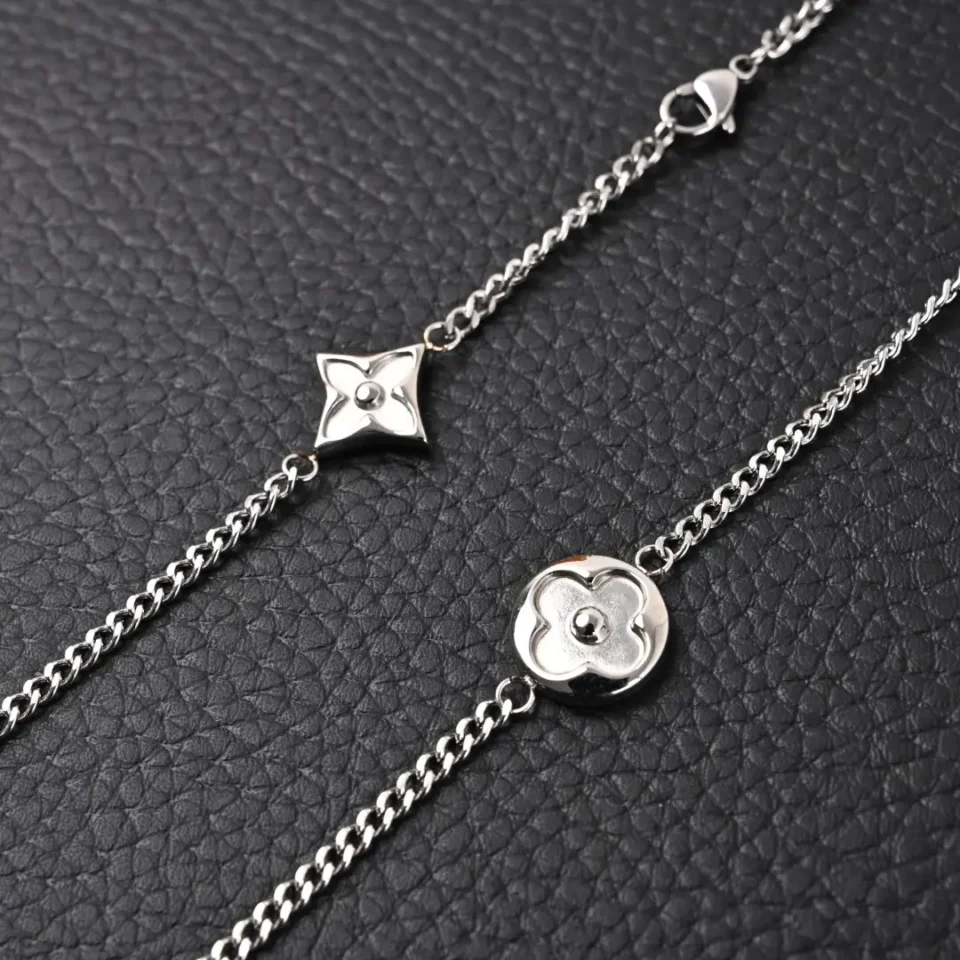 Louis Vuitton bracelet silver metal chain with flower-shaped charms on black textured background