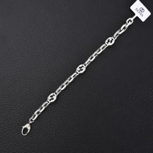 Gucci Letter Double Interlocking Silver Bracelet displayed on a black surface, featuring interlocking G logos, suitable for layering, and designed for both genders.