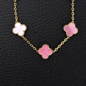 Van Cleef Arpels Classic Clover Bracelet in Sakura Pink featuring three clover motifs with gold chain, set against a textured black background.