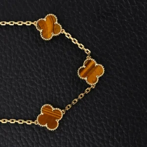 Van Cleef & Arpels replica yellow gem Fritillaria Four Leaf Clover five flower hand bracelet with intricate gold chain and clover motifs on black leather background.