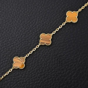 Van Cleef Arpels replica yellow gem Fritillaria Four Leaf Clover bracelet featuring intricate gold plating and unique floral design on a black textured background.