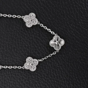 Silver bracelet featuring three clover flower motifs, showcasing intricate detailing and craftsmanship, set against a textured black background.