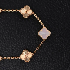 Van Cleef Arpels-inspired bracelet featuring white jade intermedullary, diamond four-leaf clover and five flower design, set against a black background.