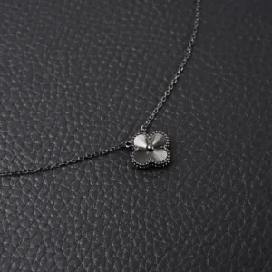 Van Cleef Arpels Flower Necklace featuring a delicate flower pendant on a sleek chain, set against a textured black background.