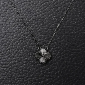 Van Cleef Arpels Flower Necklace on a black textured background, showcasing intricate floral design and elegant chain, representing affordable luxury jewelry.