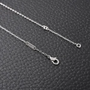 Van Cleef Arpels Classic Clover Necklace in black and blue, featuring a delicate chain and lobster clasp, set against a textured black background.