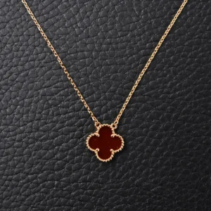 Van Cleef & Arpels Classic Clover Necklace in red pure silver, gold-plated chain, elegant clover design on textured black background.