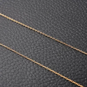 Gold plated chain necklace on textured black background, showcasing delicate design relevant to Van Cleef Arpels Classic Clover Necklace.