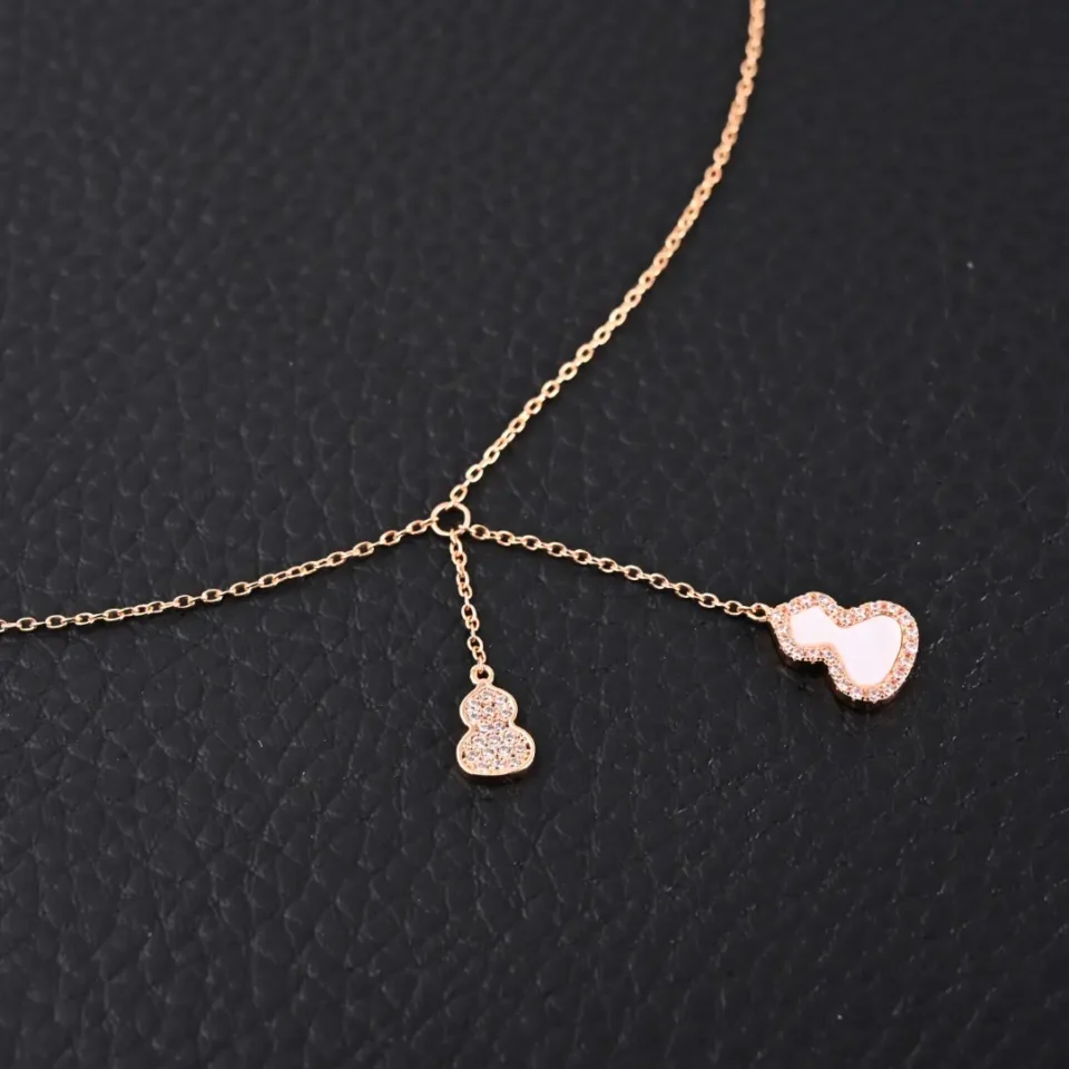 Unknown brand necklace rose gold color chain with two pendant charms on black textured background