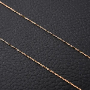 Gold-tone chain necklace against a textured black background, highlighting its elegant design and craftsmanship.