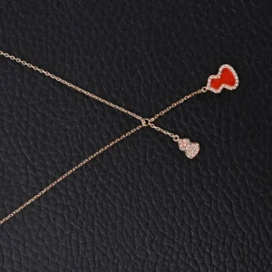 Qeelin Kirin tassel necklace featuring red agate gourd pendant and sparkling diamond accents on a delicate chain, set against a textured black background.