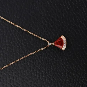 Bvlgari Diva fan-shaped necklace featuring red agate and white mother of pearl, embellished with diamonds, on a black textured background.