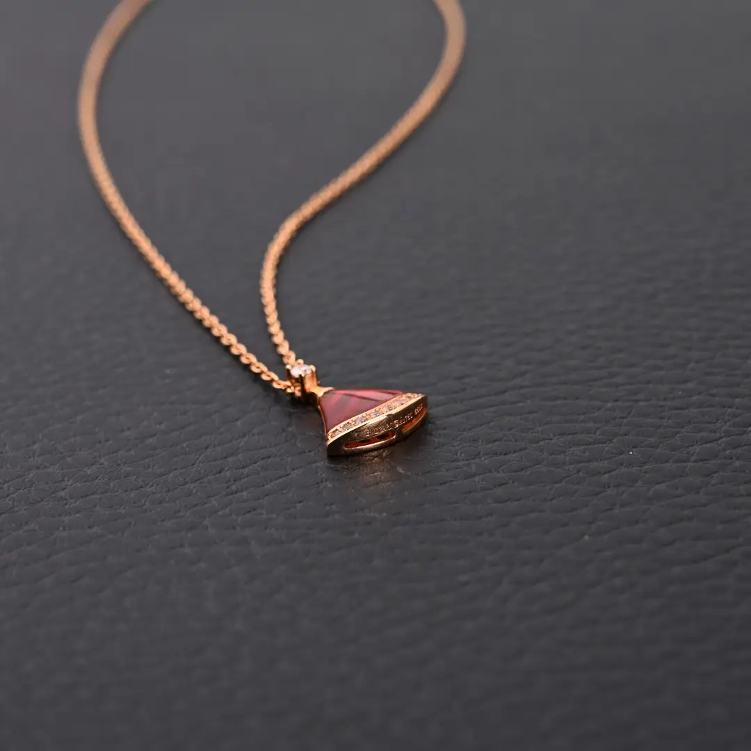 BVLGARI Diva fan-shaped necklace featuring red agate and white mother of pearl, accented with diamonds, displayed on a dark textured background.